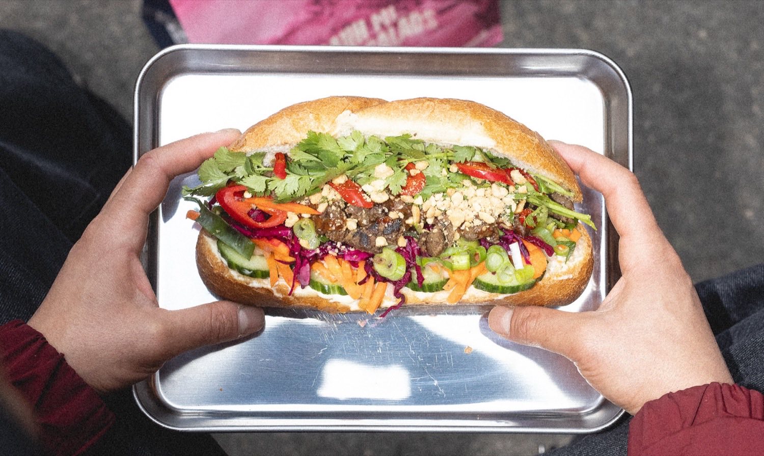 En bánh mì på stålbakke med koriander, pickles, chili og peanuts